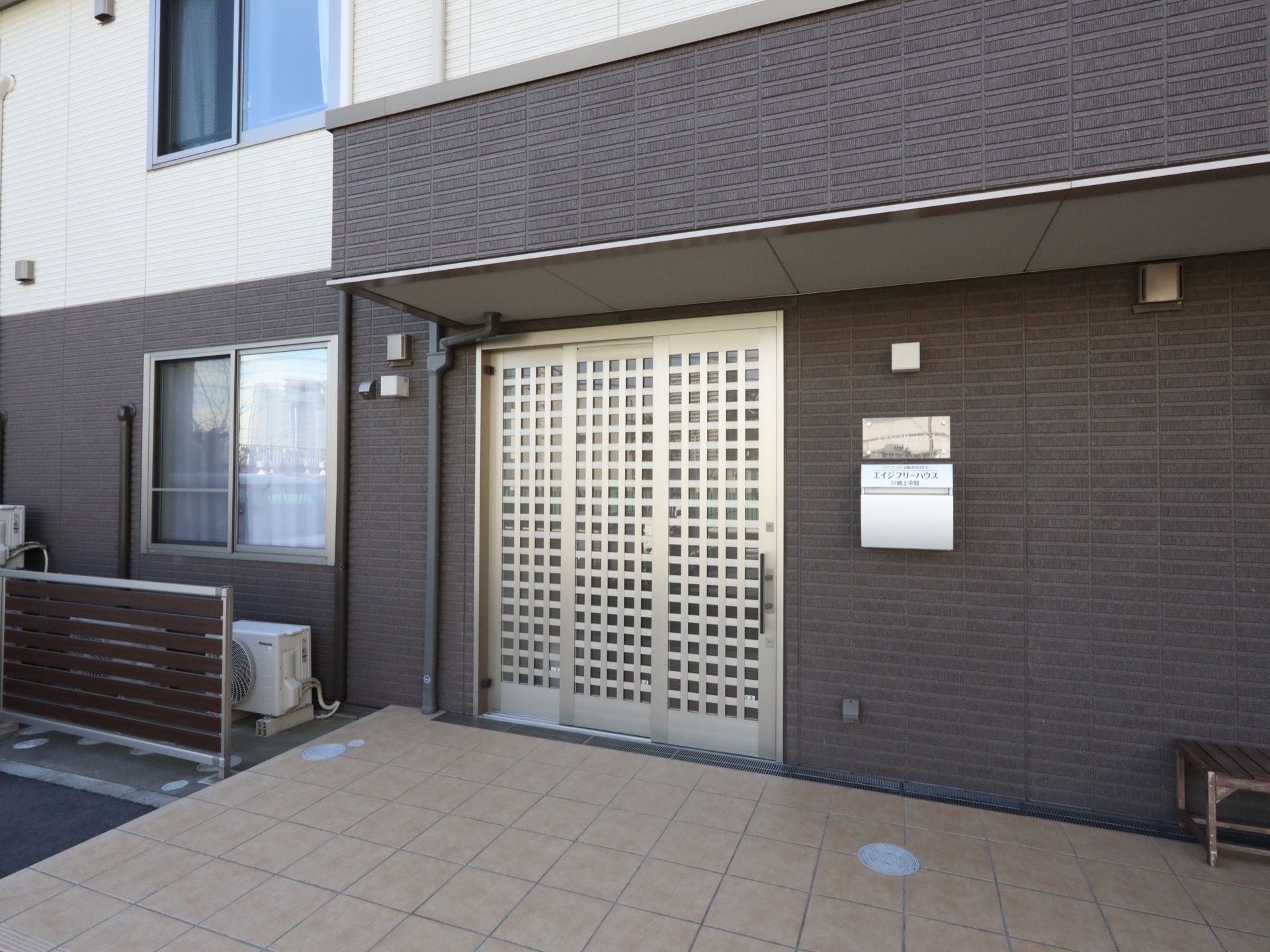 エントランスの通路には、水はけのよいタイルが使用されている。ドアは引き戸になっていて、間口が広く出入りがしやすい。