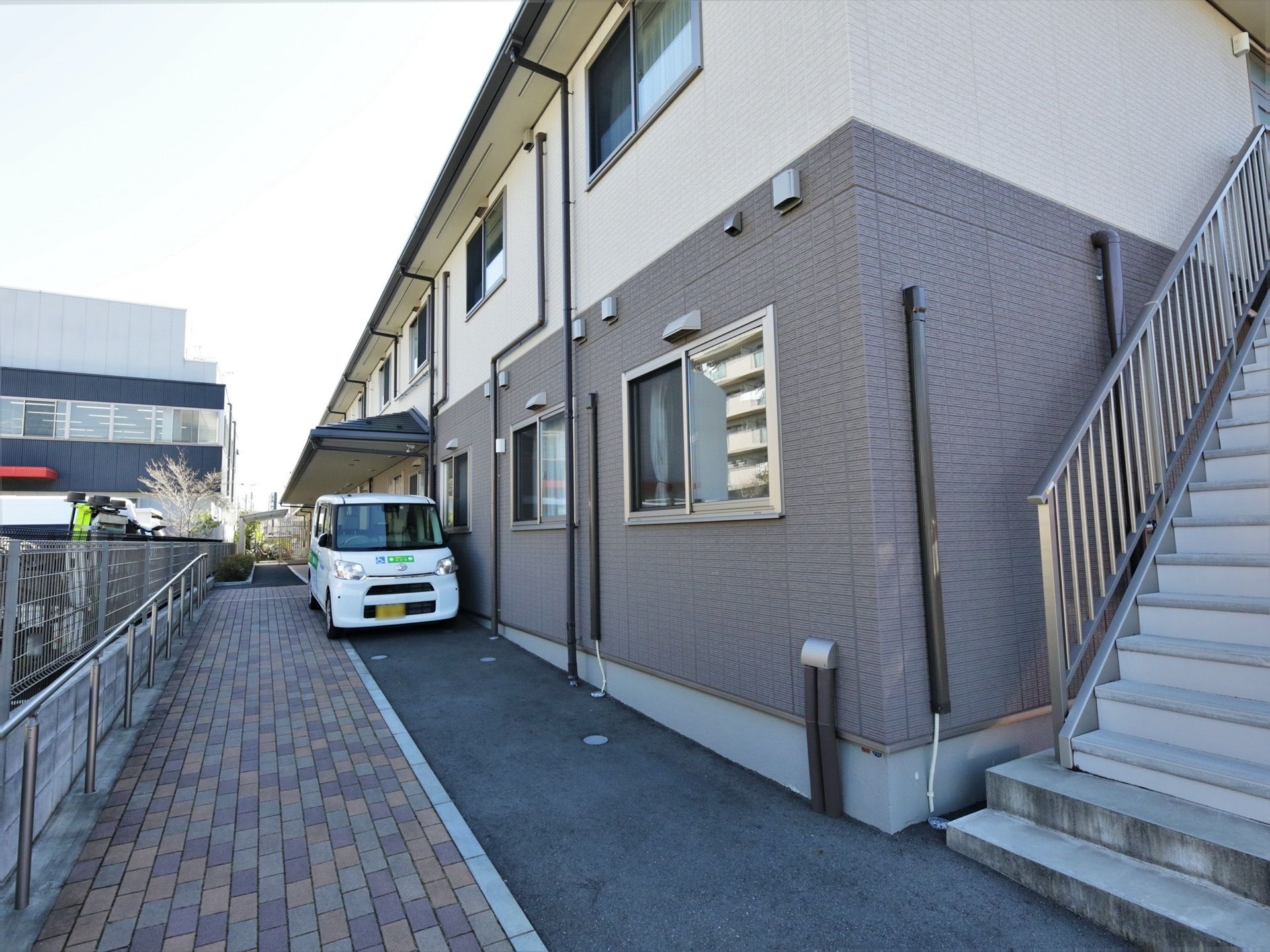 ２階建てのアットホームな雰囲気の建物である。非常用の外階段が完備されている。玄関までは手すりが備わっている。