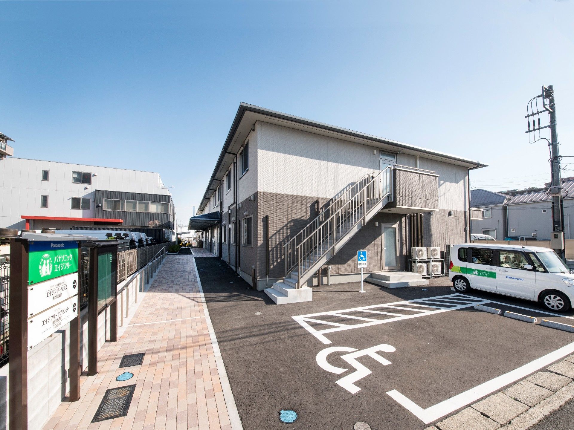 2階建ての建物の側面から見た様子。玄関には屋根が付き、2階から続く屋外階段もある。