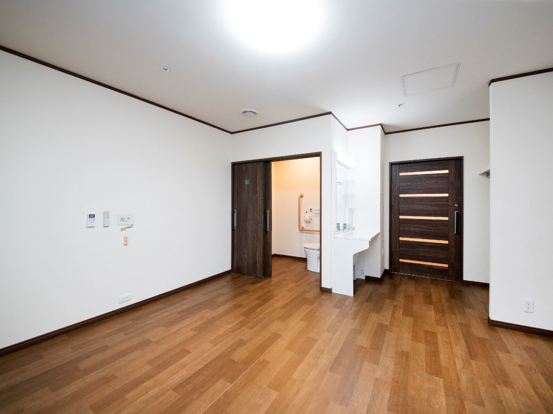家具が置かれていないシンプルな居室。フローリングでトイレや洗面所、緊急通報装置も付いている。