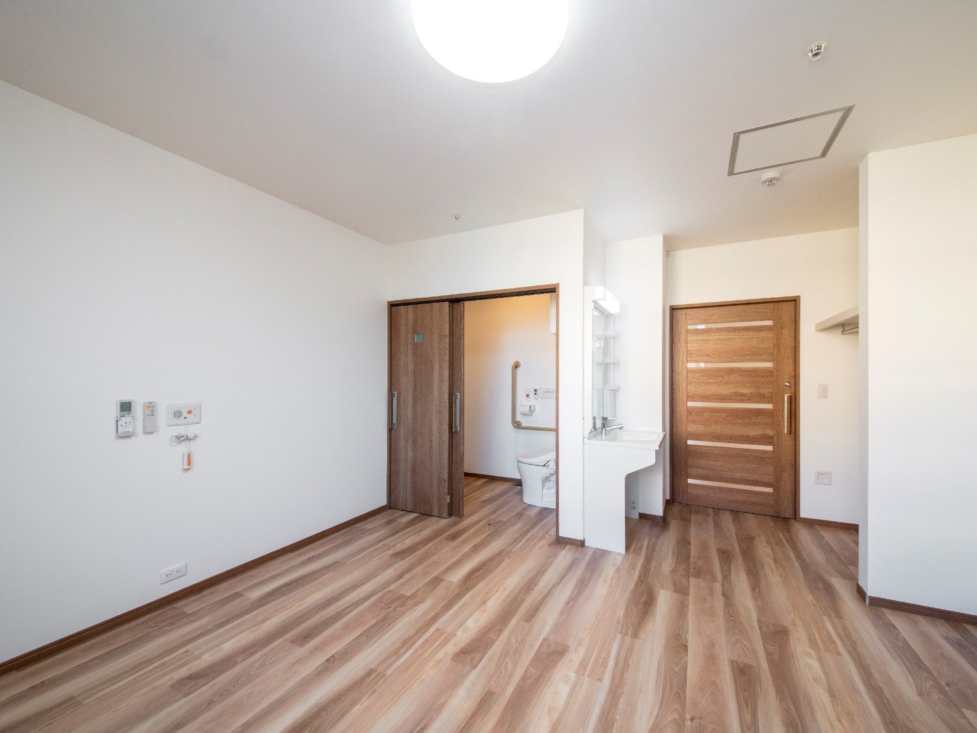大きな引き戸が付いたトイレと洗面所が付いた居室。壁には緊急通報装置が付いている。