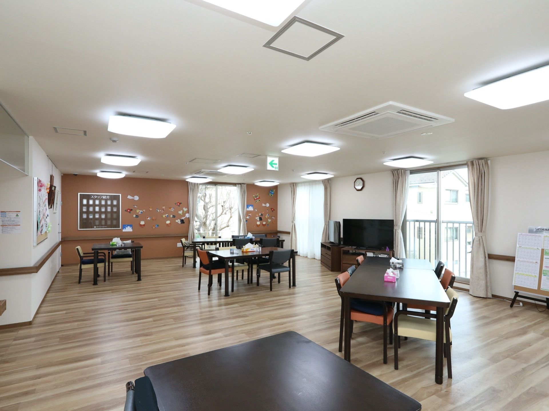 天井にたくさんの照明が設置されている、明るいリビングダイニング。大きな窓も複数設けられており、開放的な空間である。