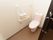 トイレは、引き戸がついたスペースに設置されている。ピンク色の便座、水タンクである。壁に大きな手すりがついている。