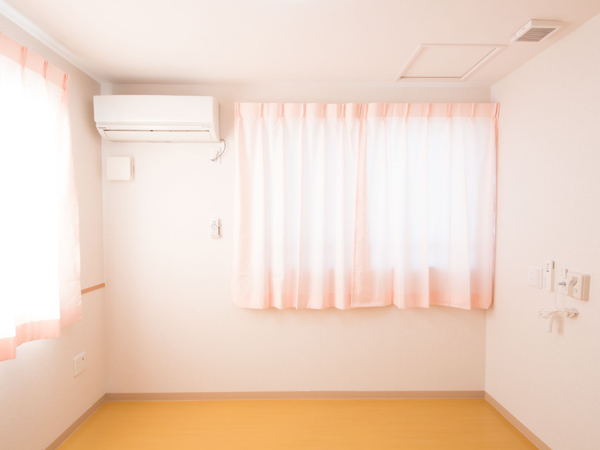 ピンクの壁とカーテンがほんわか優しい雰囲気を醸し出す居室