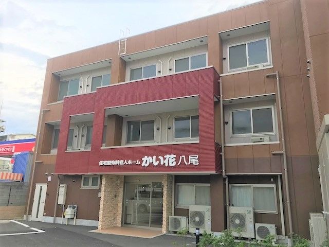 こい茶色の色合いが目を引く施設の外観。赤いふちどりがしてある看板