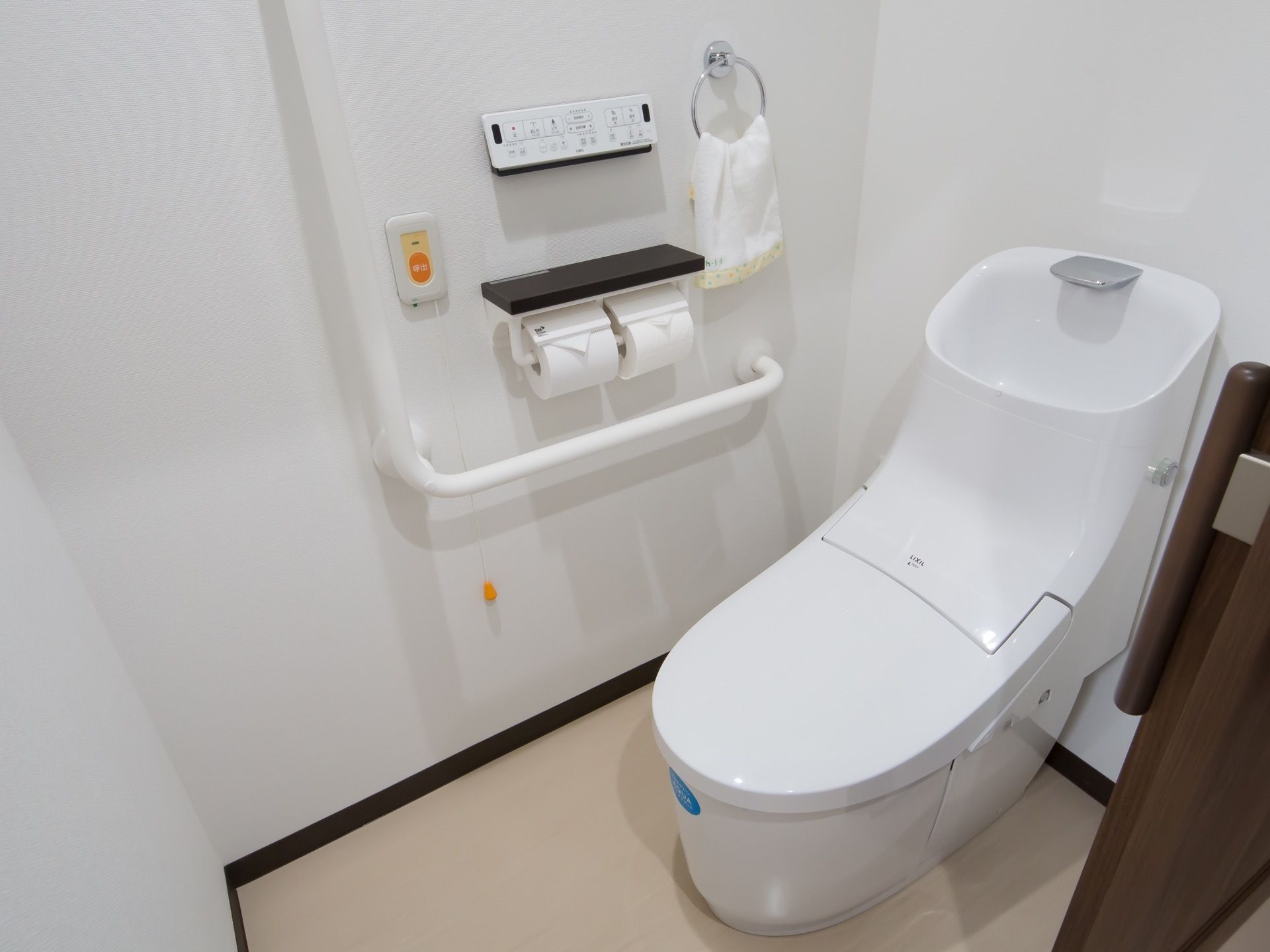 居室に備えつけられたトイレ。スライド式の扉で仕切られており、便器には手洗いスペースの設備が整っている。