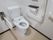 白を基調とした清潔感のあるトイレである。壁にはＬ字型の手すりや操作パネル、ナースコールが設置されている。