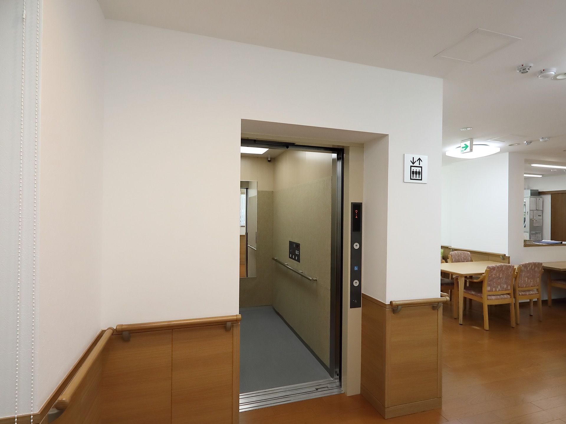 シンプルなデザインのエレベーターを完備。壁にはエレベーターのマークプレートが貼られているほか、手すりも設置されている。