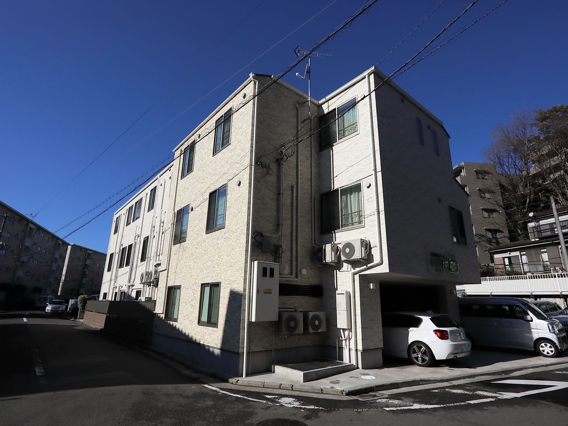 青空に映える、シンプルなデザインの建物である。目の前は道路が走っている。複数の駐車場も完備されている。