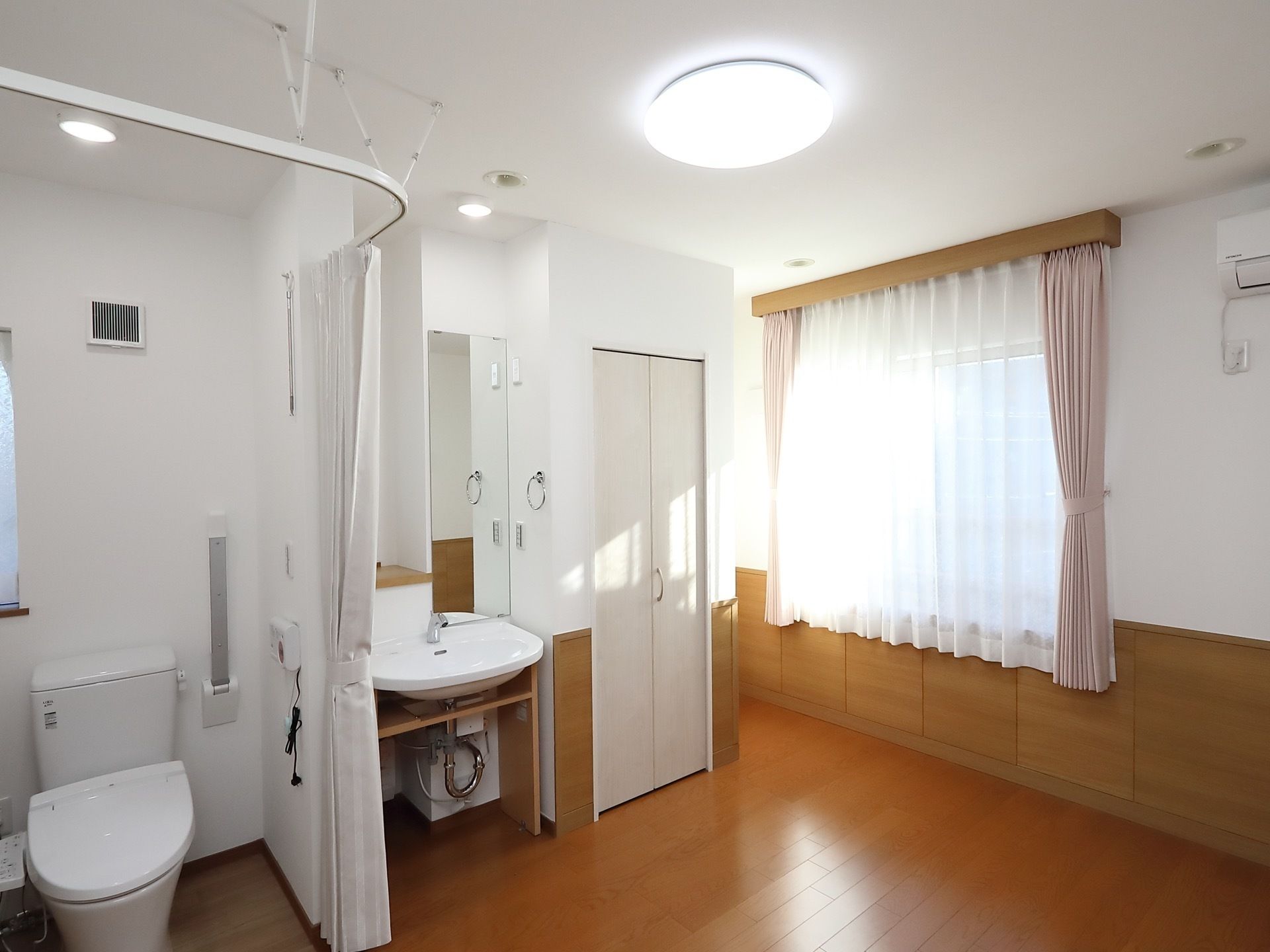 あたたかい雰囲気のフローリング部屋である。トイレは扉を設けず、カーテンが設置されている。洗面台も完備。