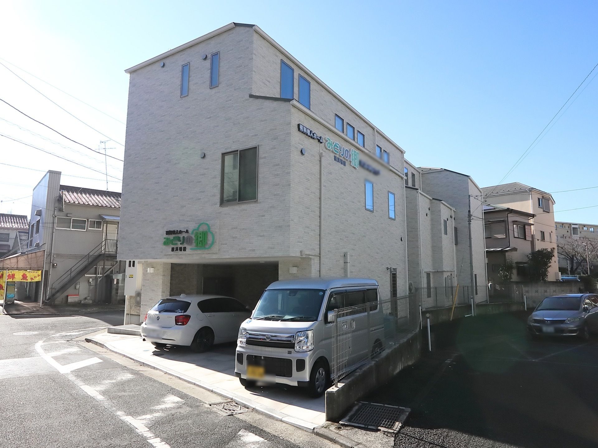 ワンカラーで統一された、シンプルな外観である。外壁に施設名が描かれている。建物のまわりにフェンスを完備。