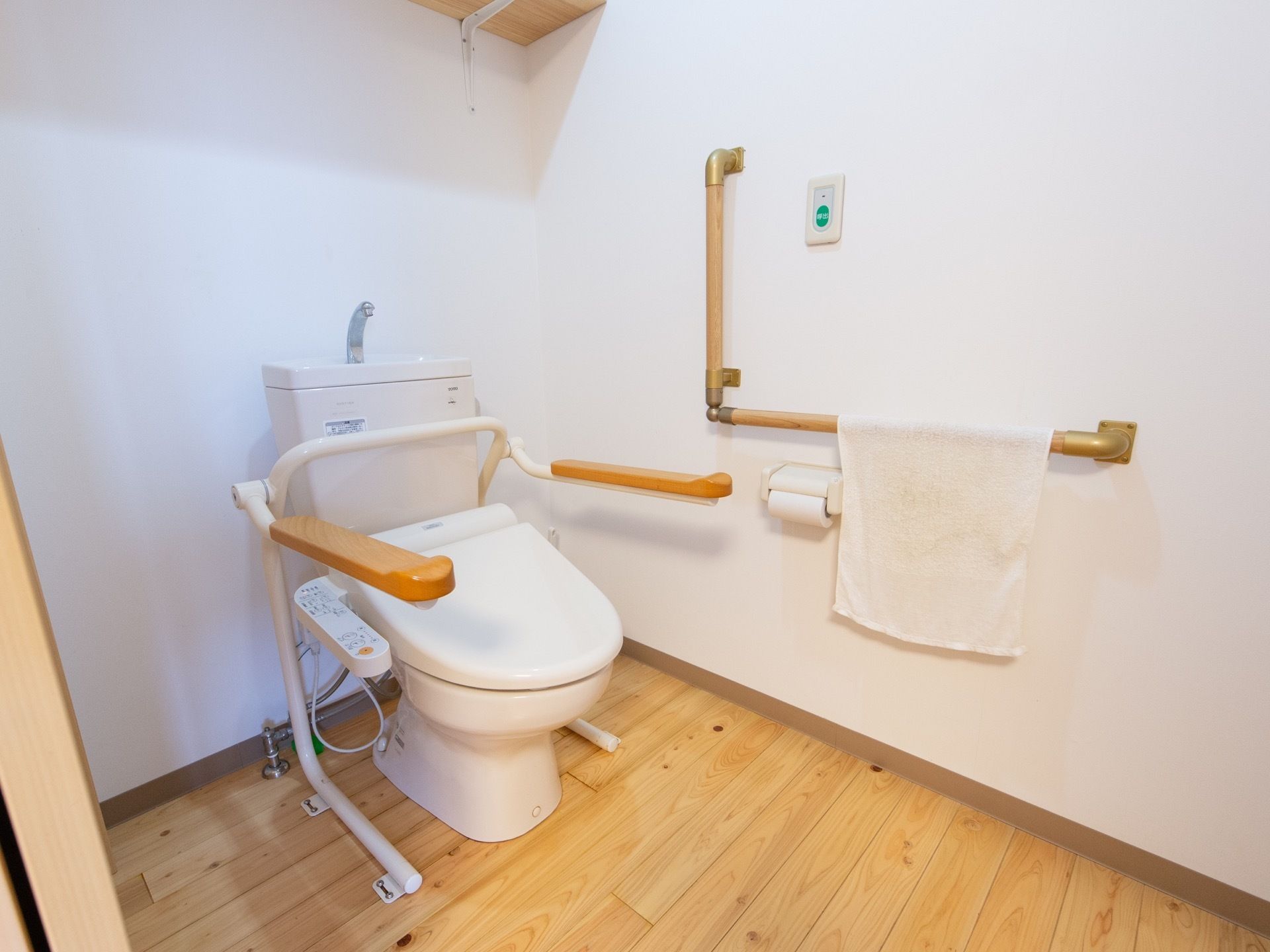 掃除がされたとても綺麗なトイレである。洋式トイレの横には、肘掛けが取りつけられ、壁にはＬ字型の手すりが設置してある。