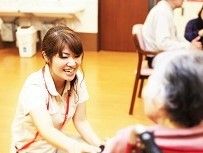 車椅子の入居者とやりとりをしているスタッフ。かがみこんで目線を下げている。