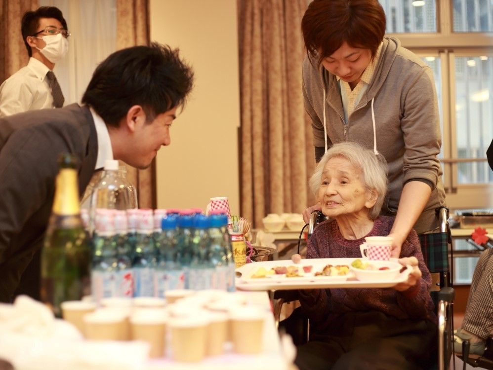 ビュッフェ形式のような食事の場面。入居者のお盆に様々な食事が並んでいる。
