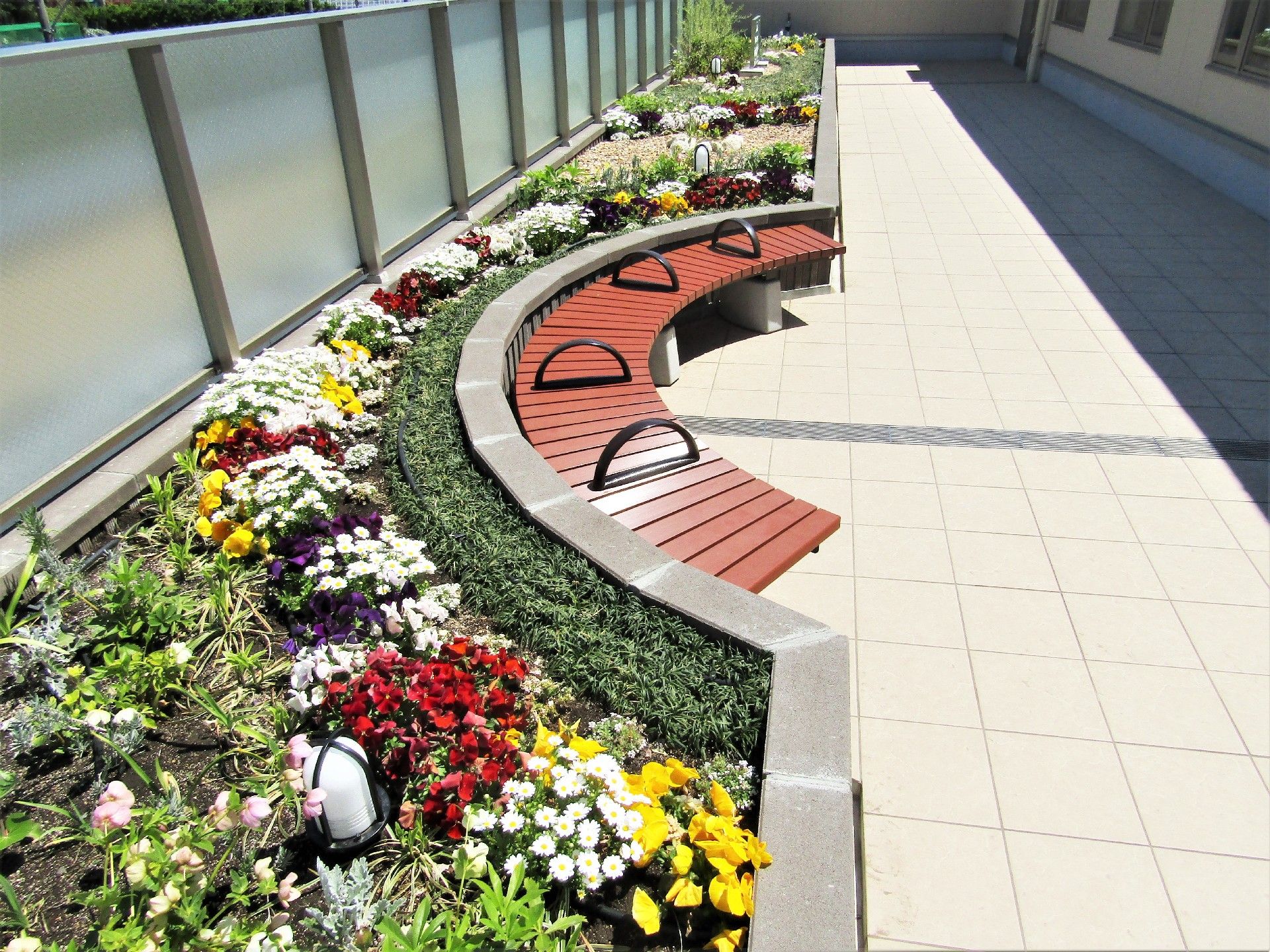 円形のベンチと花壇。花壇には赤・白・黄色の花が咲いている