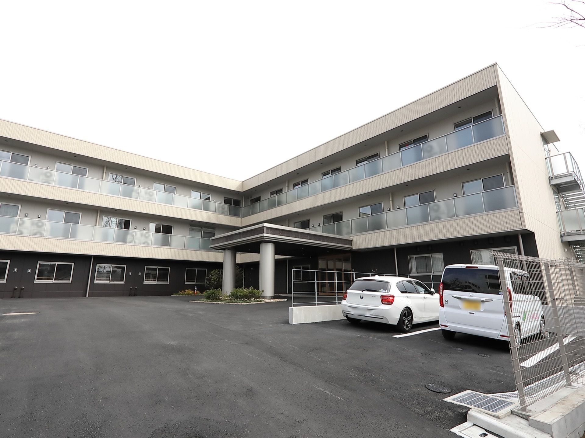 鉄骨造の建物、３階建ての横に長い建物がパースで表現してある。広めの駐車場スペース