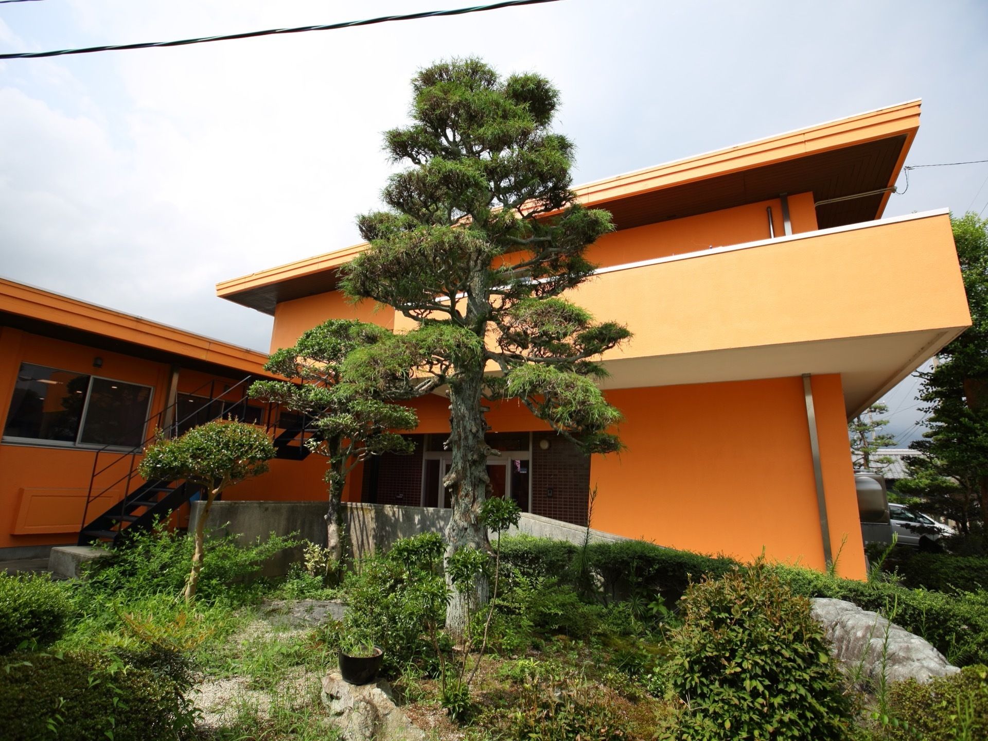 オレンジ色の外壁を持つ、一部２階建ての施設である。手入れが行き届いた背の高い木が生えている庭園がある。