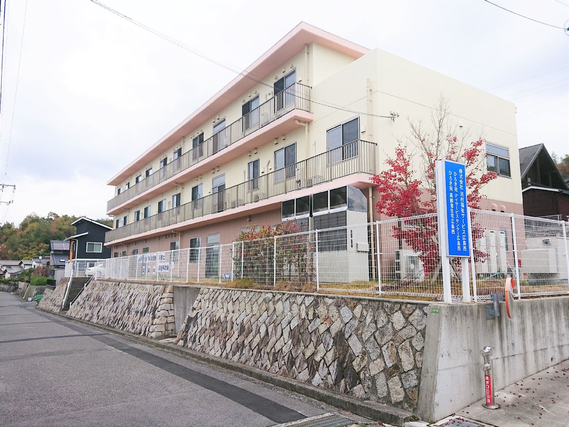 ピンク色の屋根にクリーム色の壁の建物　3階建ての1階部分の壁はピンク色になっている。