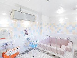 大きな浴槽が完備された浴室。右手には浴槽に入るための手すりが設置され、カラフルなタイルが明るい雰囲気。