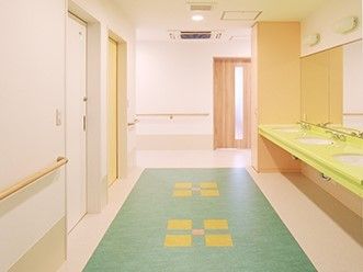 廊下のフロアはカラフルで白い壁に対してよく映える。全域に手すりが設置されている。