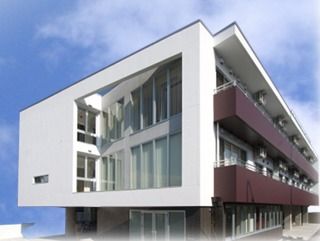 外観はすっきりとした白とブラウンの建物。３階建てで側面から見た様子。