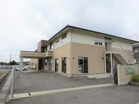2階建ての建物はベージュと白で統一されていて、建物の屋外には避難用の階段が設置されている。