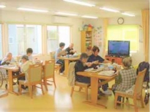 木製のダイニングテーブルにはいすがセットされ、明るいスペースで食事をとっている入居者の様子。