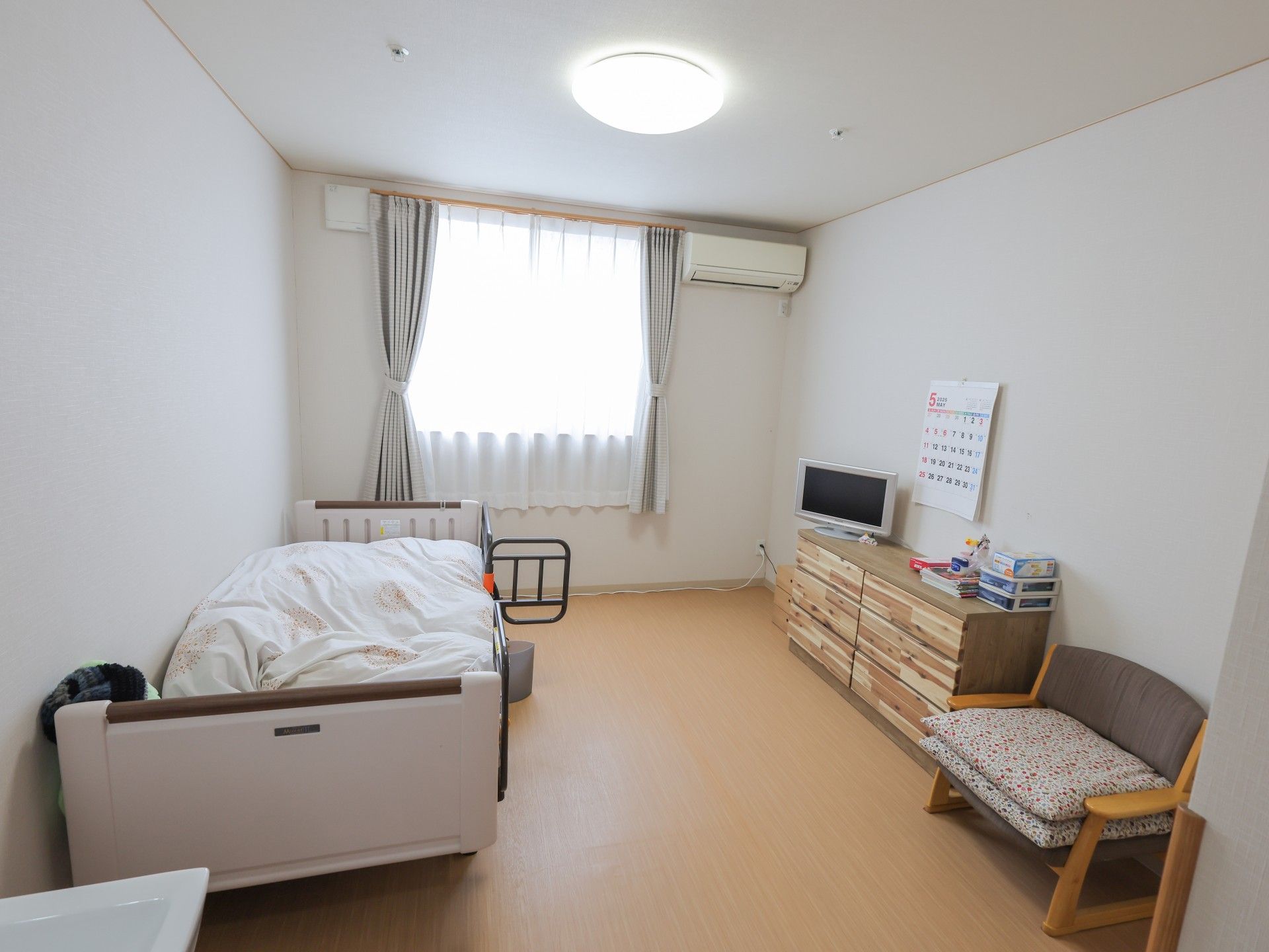 大きな窓が付いた居室は日当たりがよく明るい。ベッドやエアコンなどが設置されている。