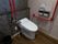 共用トイレの横は、ダークな色合いのフローリングとなっている。手すりは固定のものと可動のＵ字型のものがあり、赤色をしている。