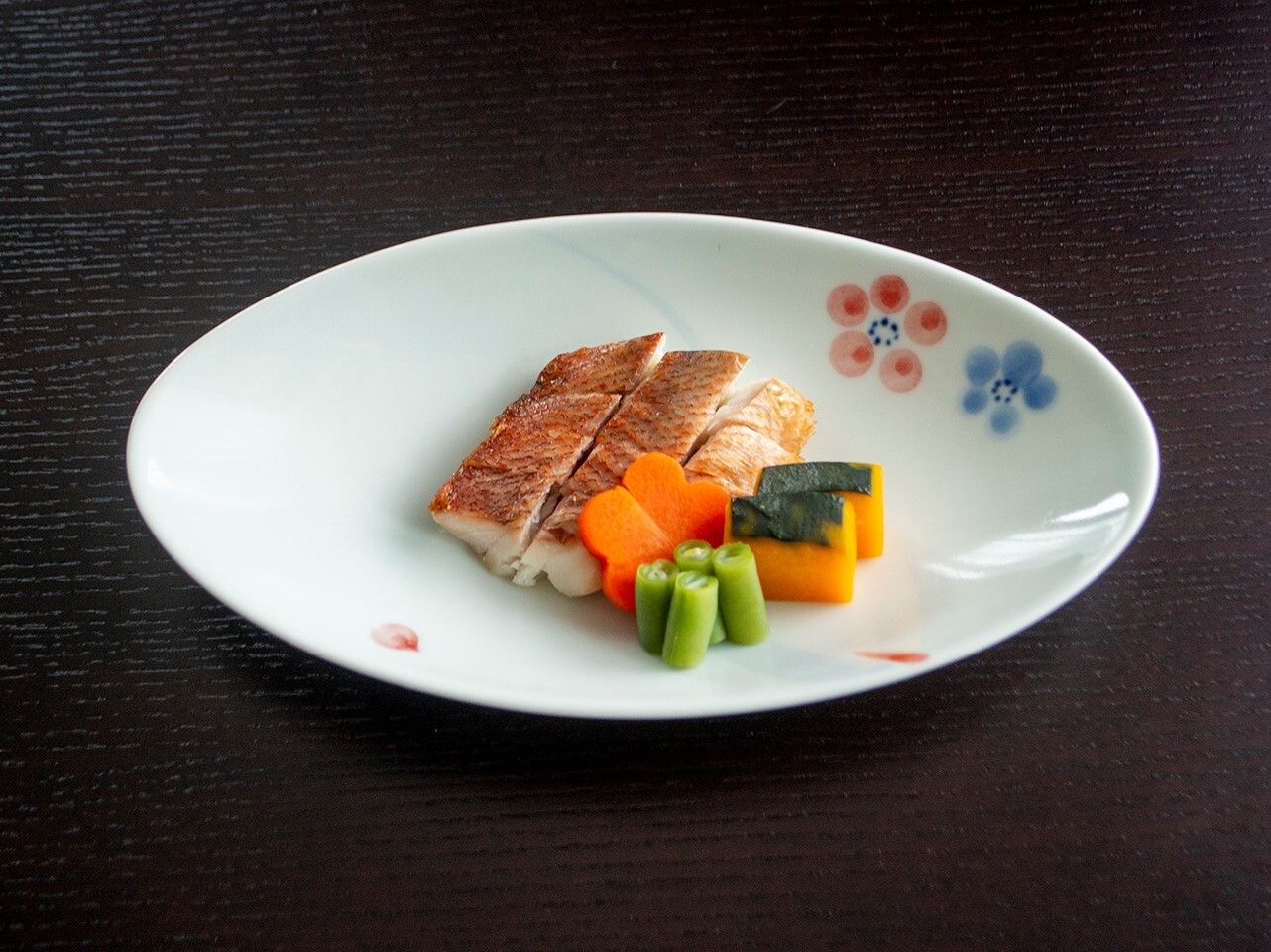 小さく切られたチキン。添えられているカボチャやにんじん、いんげんも小さく切られている。にんじんは花の形。