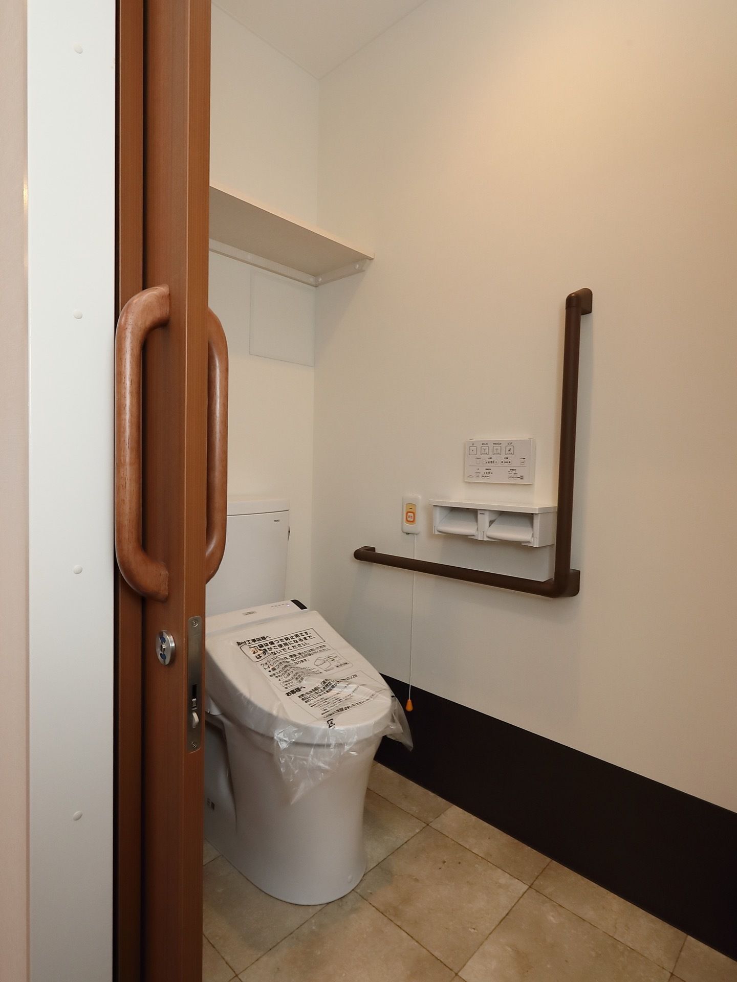 温水洗浄便座付きのトイレが用意されている。壁にはL字型の手すりとペーパーホルダー、緊急呼び出しボタンが備えつけられている。
