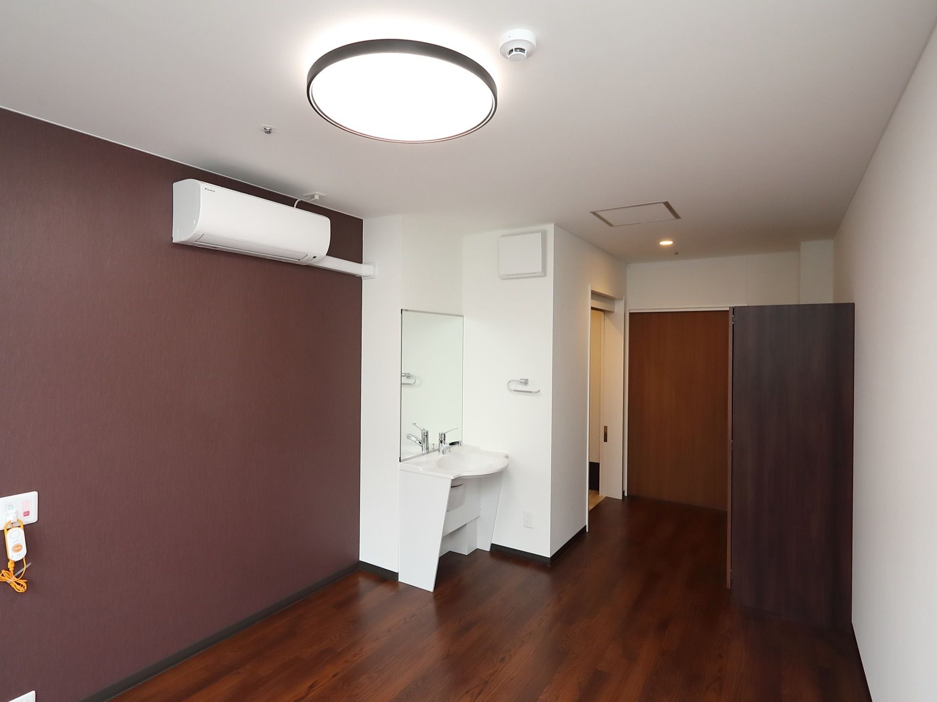 シックなカラーが印象的な個室になっている。部屋には洗面台、クローゼットが用意されており、エアコンと照明が完備されている。