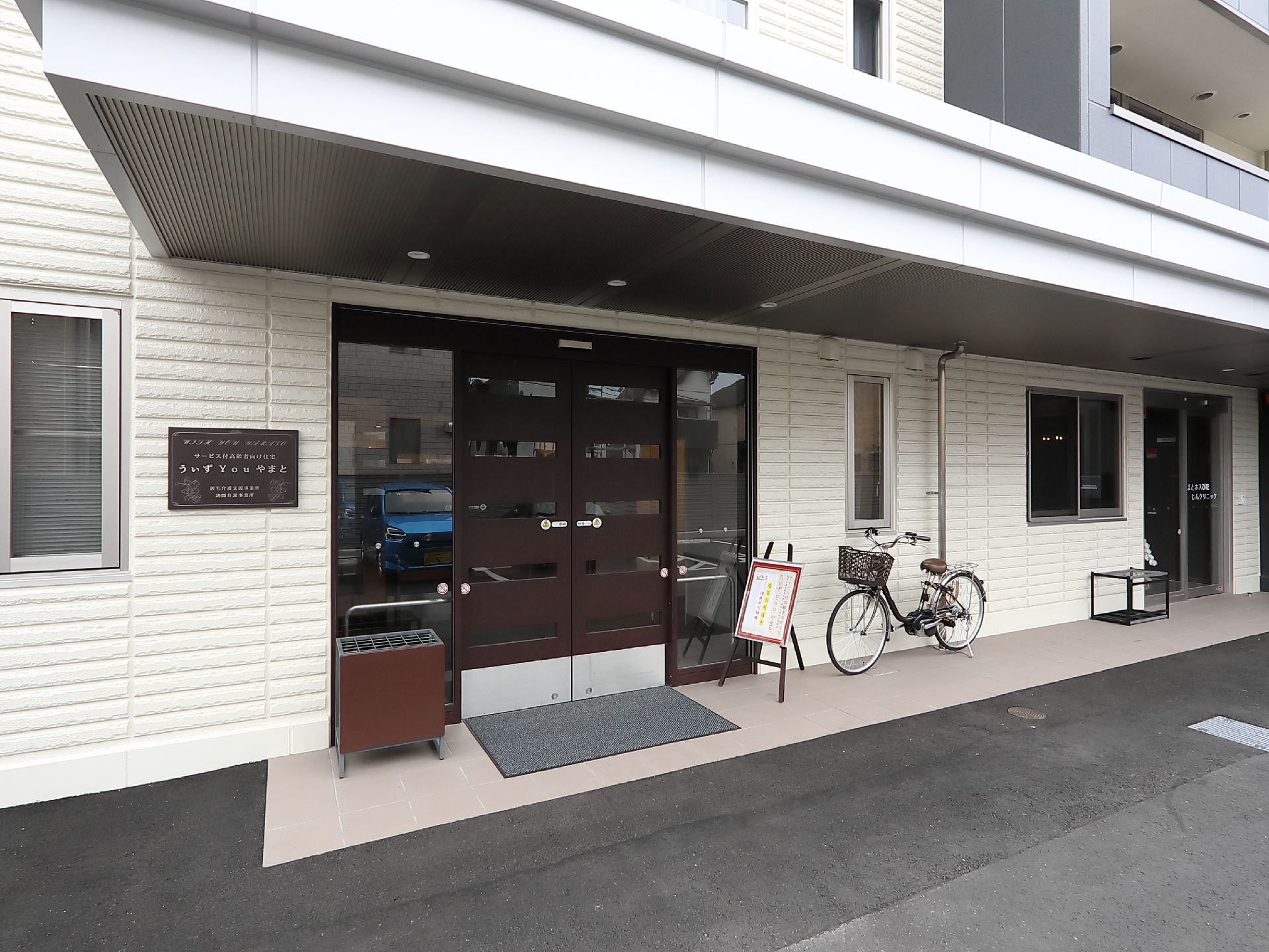 白のレンガ調に茶色の木枠の入り口で落ち着いた雰囲気のある玄関口