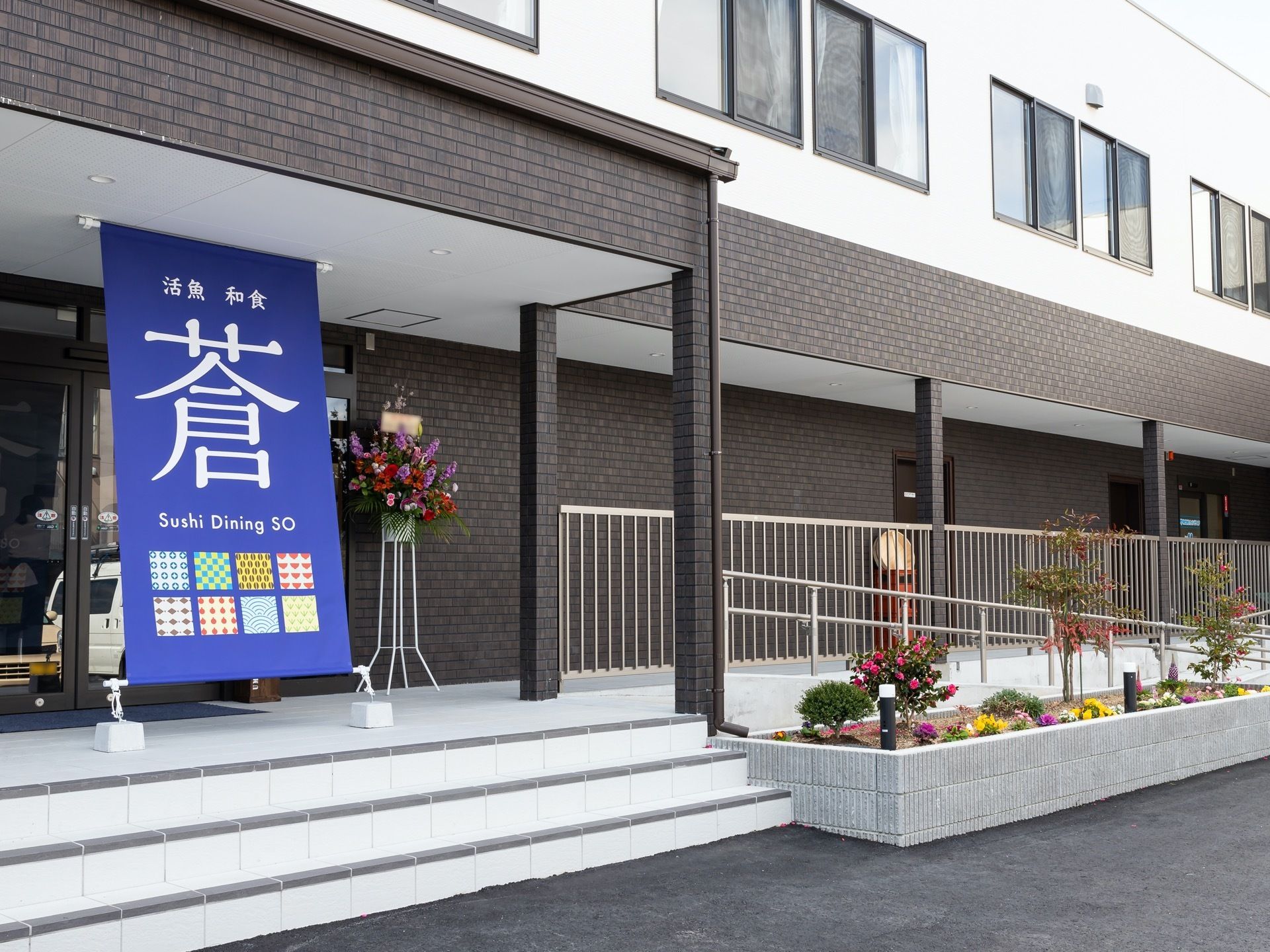 濃いブラウンを基調とした高級感のある建物である。入り口までは、階段とスロープがある。スロープには手すりがある。