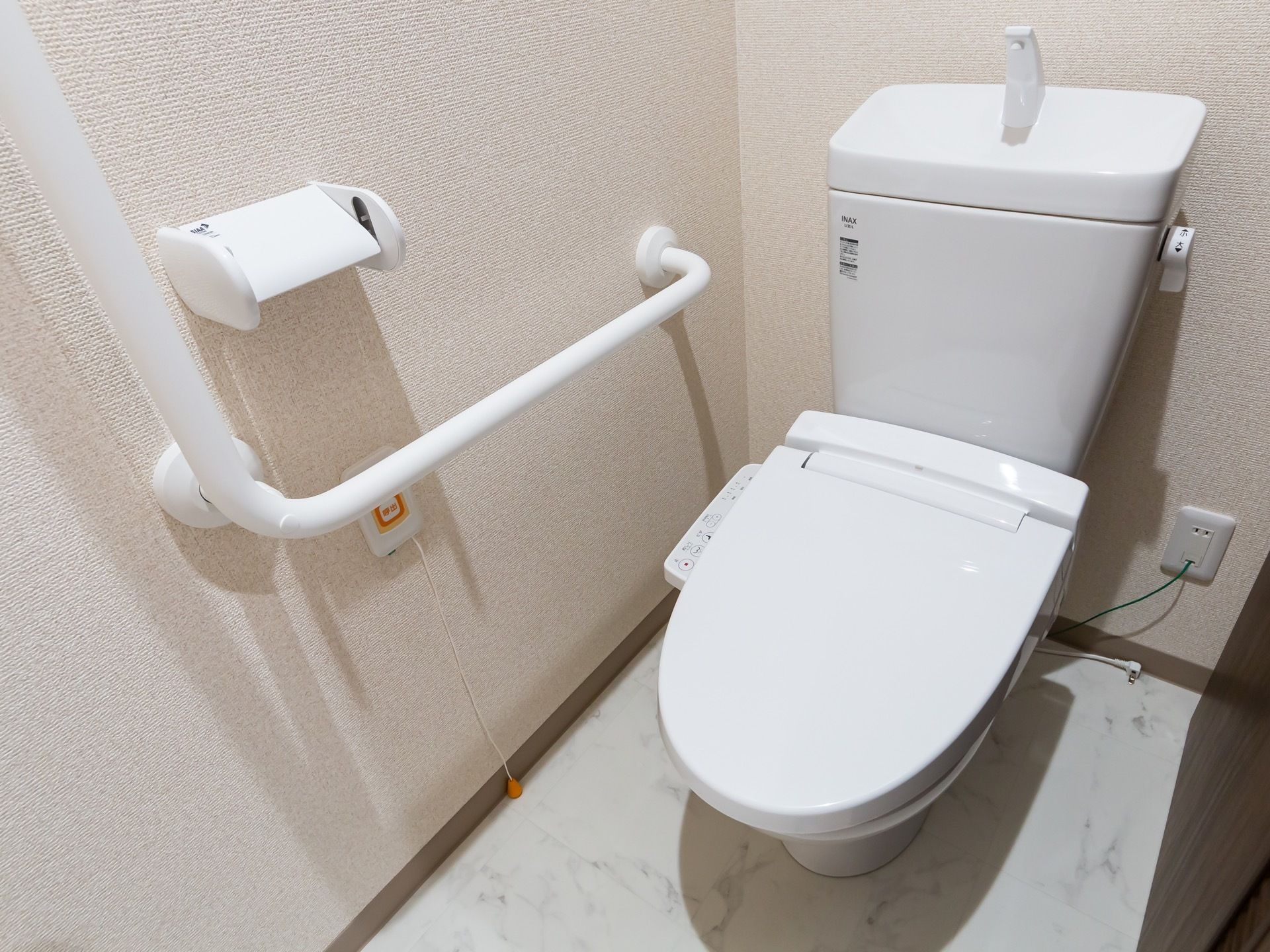 トイレの壁には手すりがある。その下には緊急用ブザーが用意してあり、安全面に配慮されている。