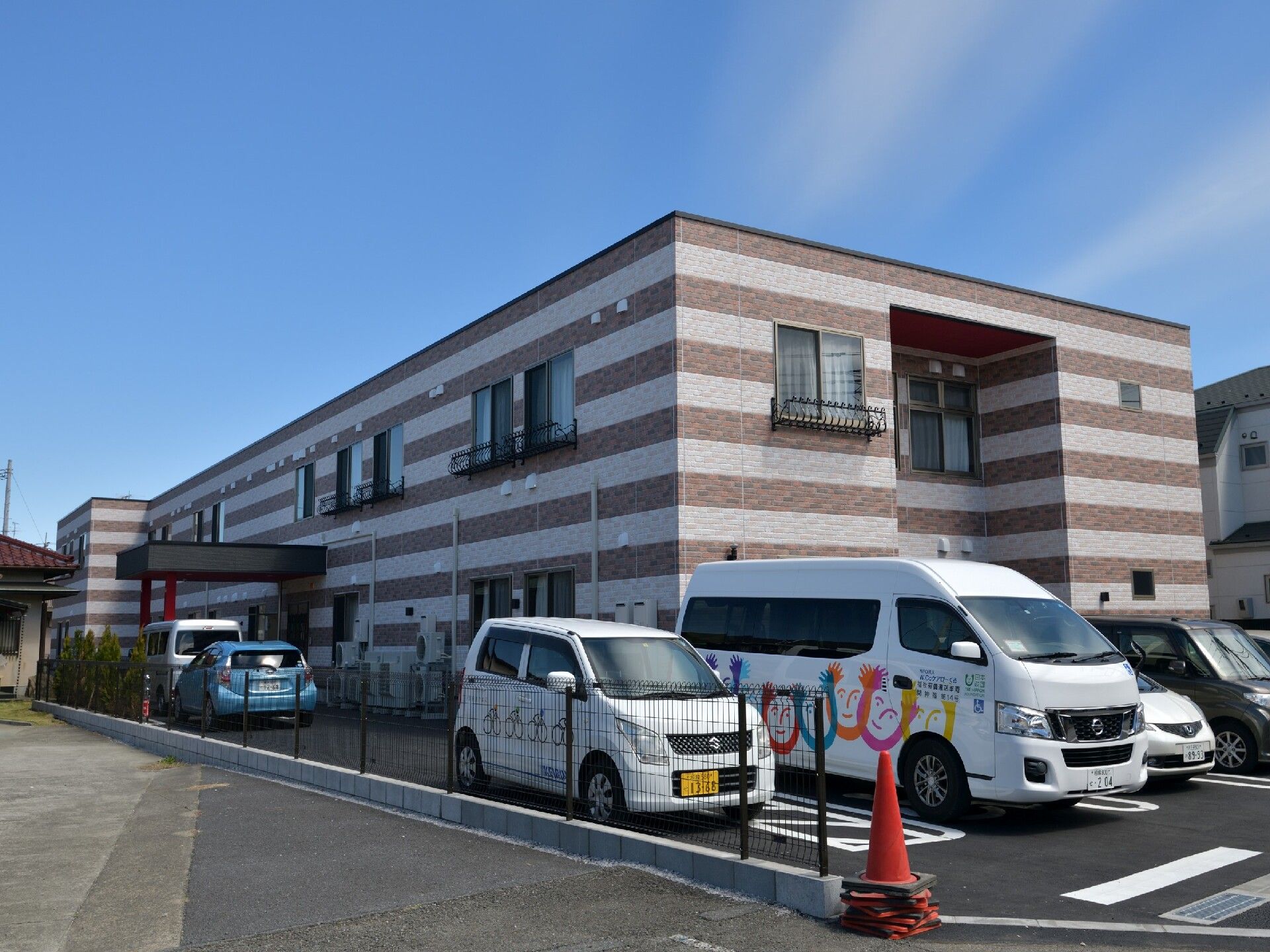 ストライプの外壁がスタイリッシュな建物。２階建てで玄関には車寄せが付いている。