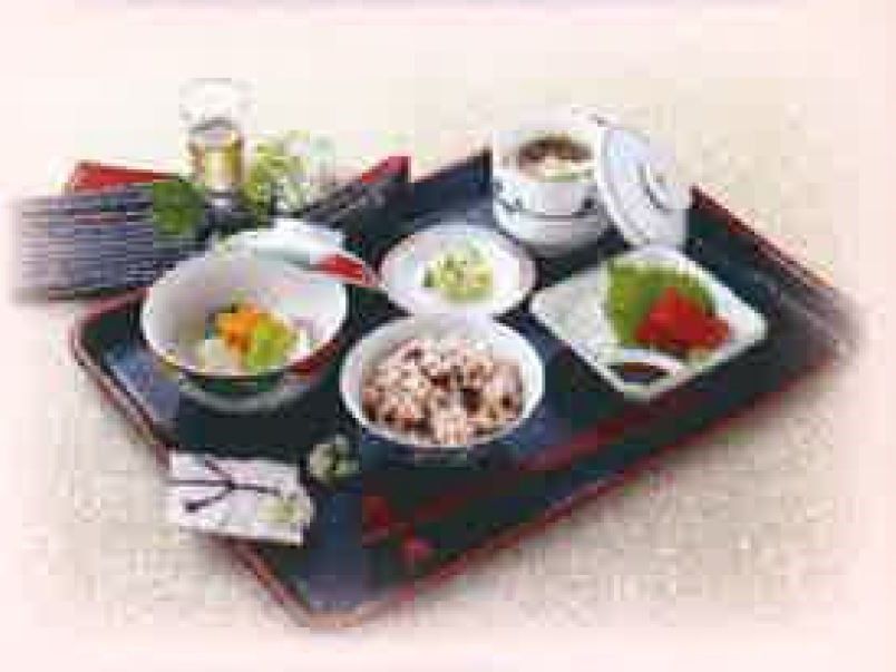 黒いお盆の上にはきれいに盛り付けられた料理がある。赤飯と吸い物、メインの刺身と小鉢。