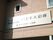施設の外壁に施設名の書かれたクリーム色の看板が設置されている。外壁は茶色で、窓が２箇所設けられている。