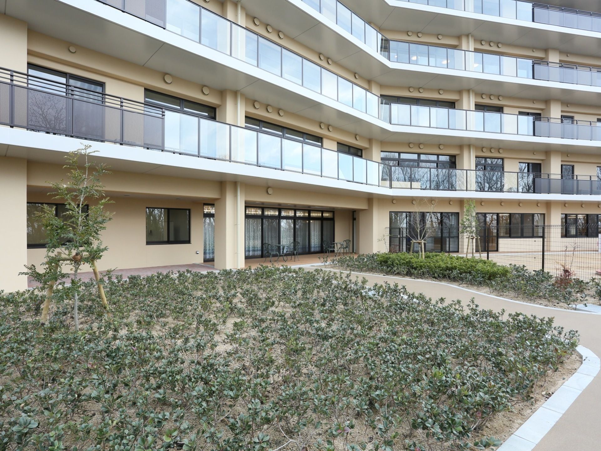 施設は大きな建物になっており、２階以上にベランダが設置されている。建物の周りには、たくさんの木々が植えられている。