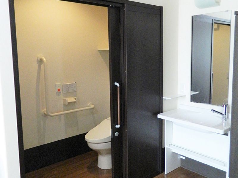引き戸付きのトイレにはエル字型の手すりや呼び出しボタンがあり、トイレを出ると洗面所がある。