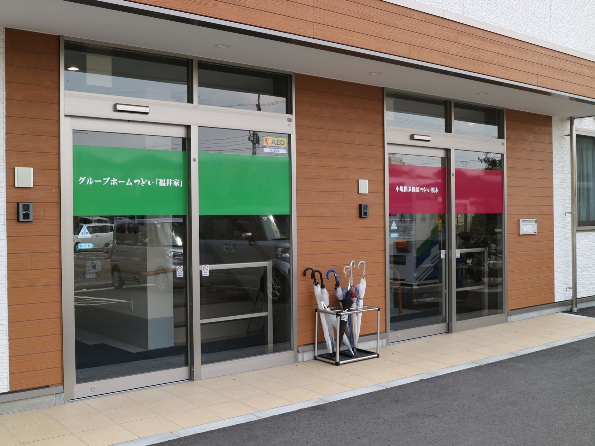 自動ドアが２つ設置されており、間には傘立てが置かれている。敷地内には、アスファルトで舗装された駐車場が完備されている。