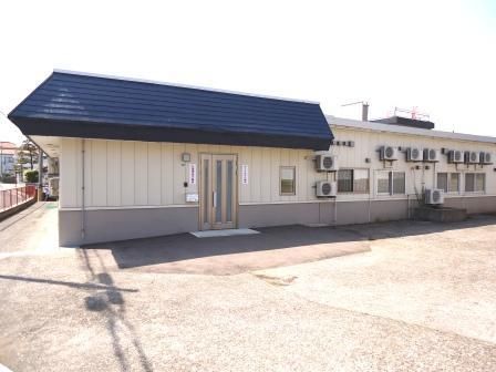 広めの駐車場スペースと建物が写っている。平屋建ての建物の写真