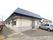平屋建ての建物である。外壁にはエアコンの室外機がかかっている。玄関前には車が1台停められている。