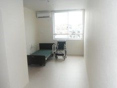 奥のほうにベッドやいすがある窓付きの部屋。小さなワンルームタイプの部屋の写真