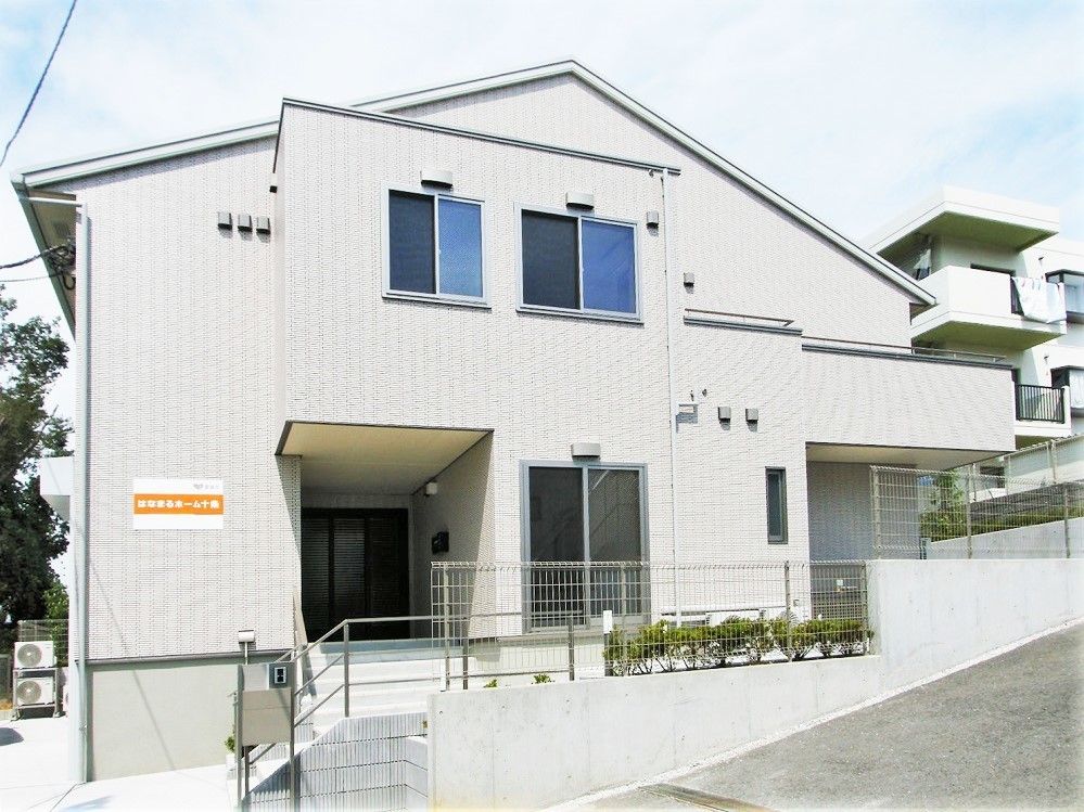 ２階建ての建物は三角屋根に白い外壁、そして玄関前には屋根が付いている。