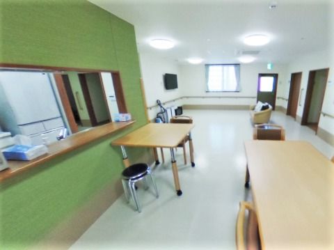 手すりが設置された共有スペースにはダイニングテーブルが複数置かれ、奥にはソファスペースもある。