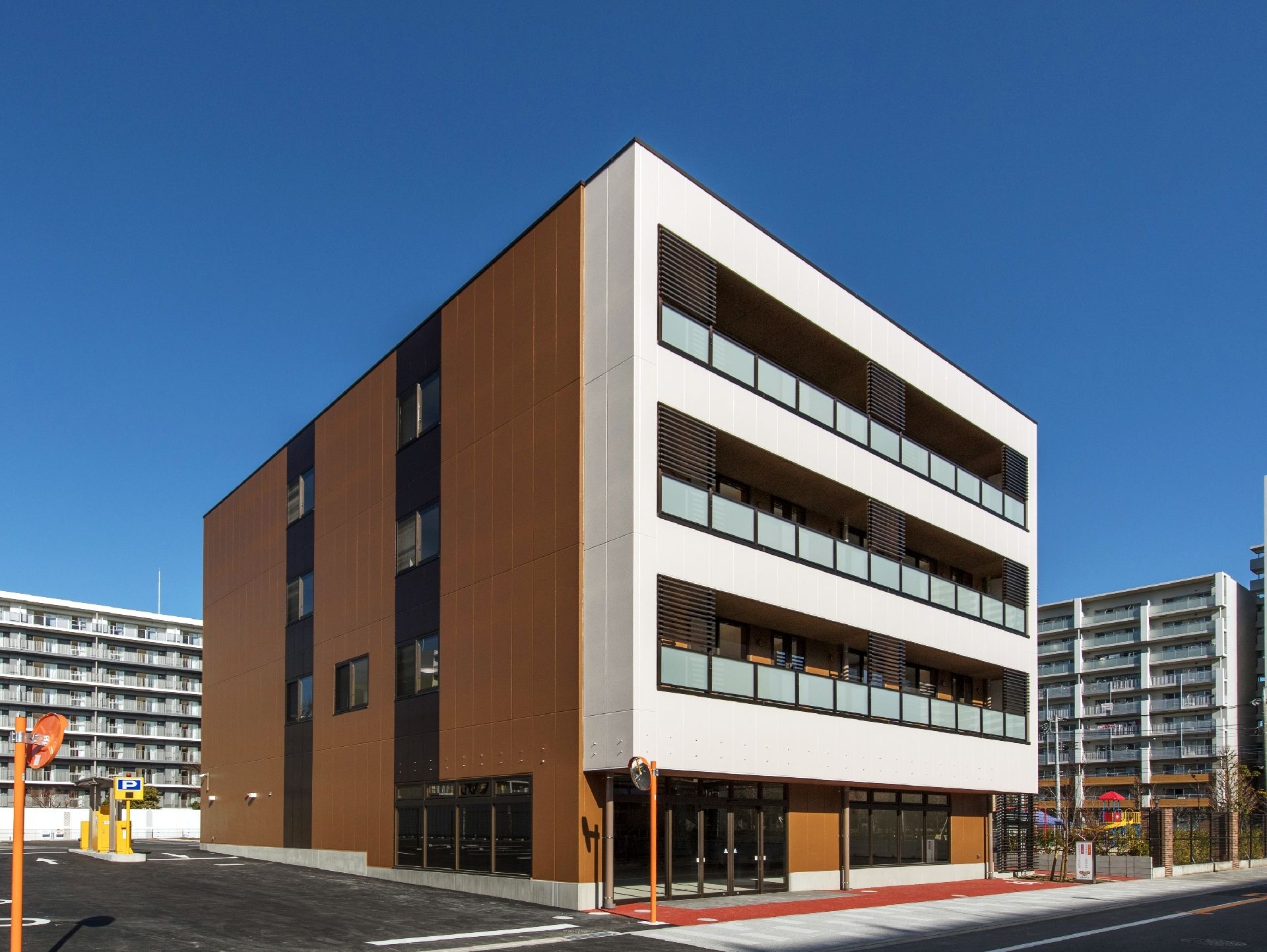 ４階建ての四角い建物。正面は白く、側面はブラウン。