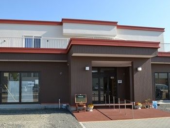 ２階建ての建物の写真。赤く縁どられた屋根部分が印象的な建物
