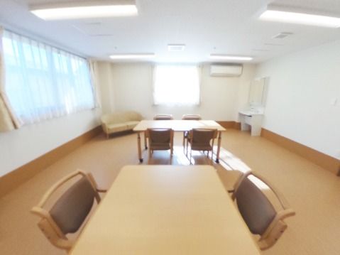 リビングダイニングは広く、ダイニングテーブルセットが二つ中央に置かれ、隅にはソファや洗面所がある。