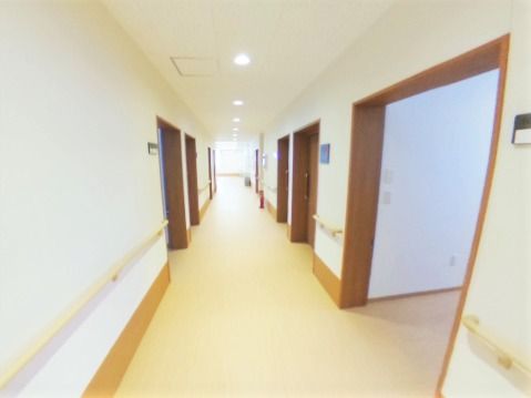 廊下はまっすぐで居室周りの枠だけブラウン、手すりはベージュ、壁は白。